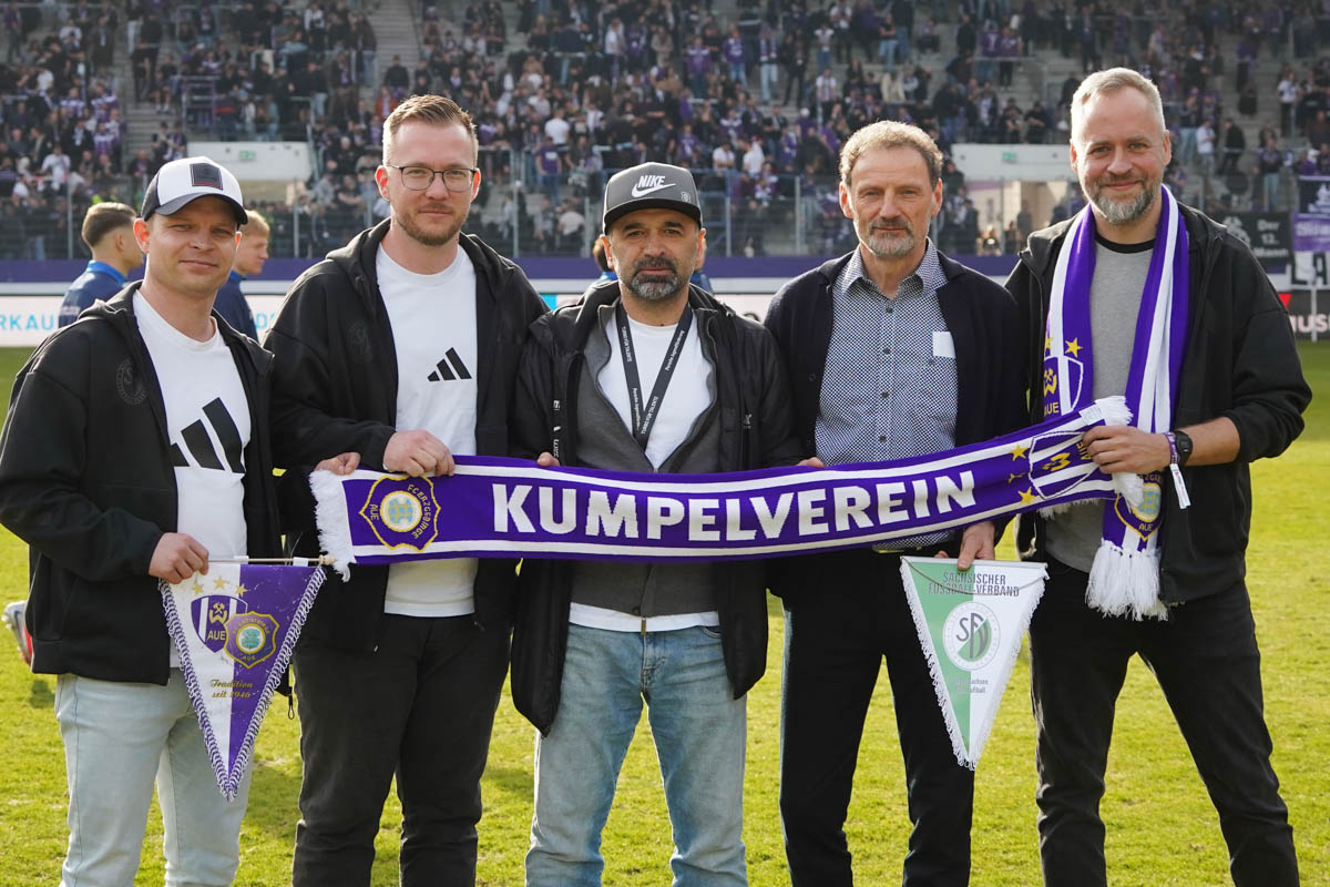 Verantwortliche vom SFV und FC Erzgebirge Aue mit einem Aue-Schal im Stadion.